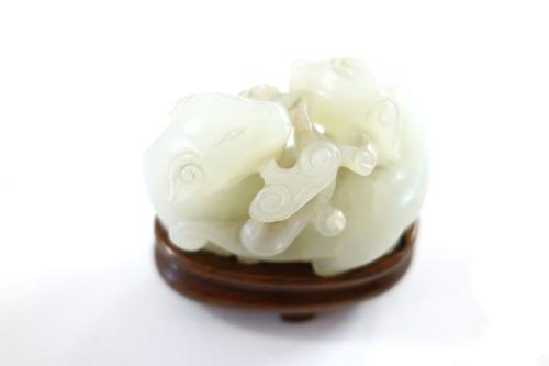 A Chinese white jade group of two cats, Qing Dynasty, 18th/19th century, each holding a sprig of lingzhi  in its mouth, 5cm.length, later wood stand.