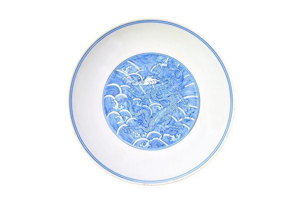 A Chinese blue and white dragon saucer dish, Qianlong seal mark and probably of the period, painted in the centre with a dragon amongst breaking waves