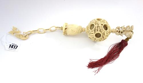 A Chinese ivory concentric puzzle ball, late 19th century, the ball carved on the exterior with figures amongst pavilions and trees, above a cluster o