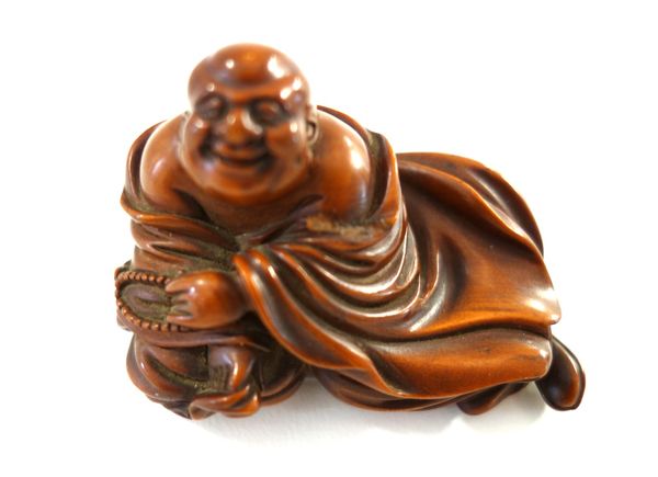 A Chinese carved wood figure of Budai, Qing dynasty, the corpulent monk resting against a sack, holding prayer beads in his left hand, 7cm. length.