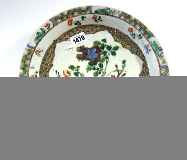 A Chinese famille-verte plate, Kangxi, painted with a barbed panel enclosing flowering shrubs and rocks, the rim reserved with small flower and rock p