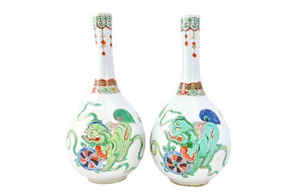 A pair of Chinese famille-verte bottle vases, Kangxi, each painted with buddhist lions and ribbons, (a.f), 27cm.high. Illustrated