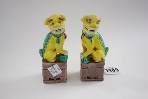 A small pair of Chinese porcelain Buddhist lions, 20th century, each seated with one paw resting on a brocaded ball, 11.5cm. high, cased