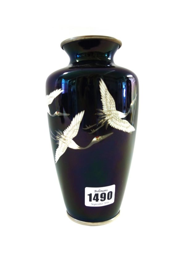 A Japanese cloisonné vase, Meiji period, of slender ovoid form, worked with three cranes in flight against a black ground, 18.5cm.high.