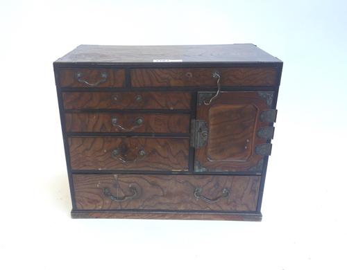 An early 20th century Japanese elm table cabinet, with an arrangement of doors and drawers, on a plinth base, 39cm wide.
