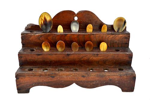 A George III elm and softwood three tier waterfall spoon rack, with assorted bone and horn spoons, on a shaped plinth base, 40cm wide. Illustrated