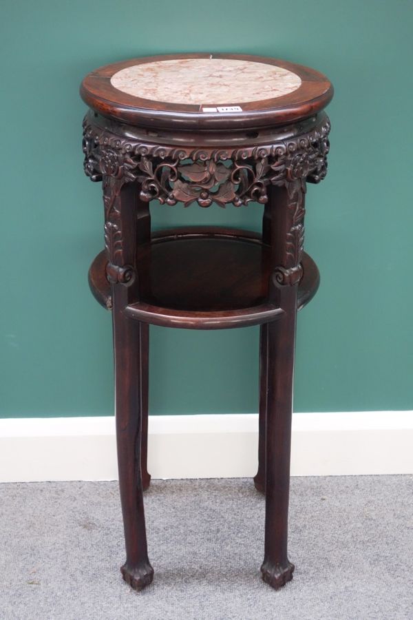 An early 20th century Chinese jardiniere stand, the circular marble inset top over carved frieze, on four ball and claw feet, 40cm wide.