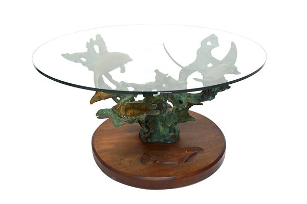 A 20th century coffee table, the circular glass top on a bronze base with dolphin, turtle and stingray amongst coral, 91cm wide. Illustrated