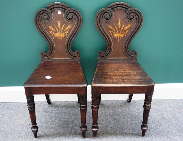 A pair of 19th century oak hall chairs, the shaped backs with painted crown and corn decoration over solid seats on turned supports, (2).