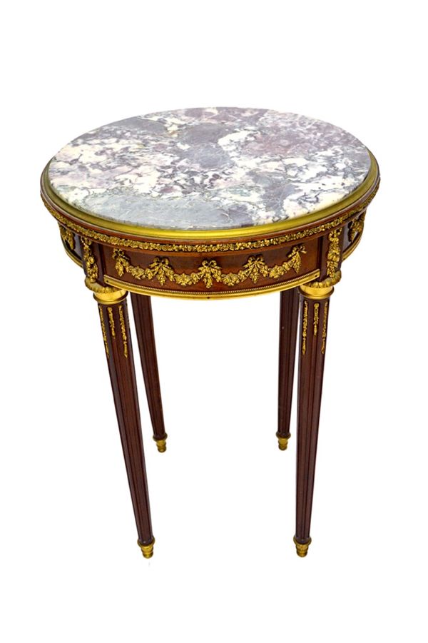 A Louis XVI style gueridon, the circular marble top on a gilt metal mounted mahogany base with four tapering fluted supports, 51cm wide. Illustrated