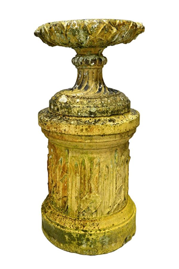 In the manner of Coade Stone; a late 19th century garden urn, with spiral fluted socle, on a circular stand relief moulded with lilies and rushes, 51c