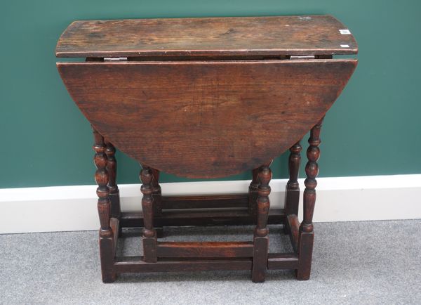 A late 17th century elm drop flap table, on turned supports, 70cm wide.