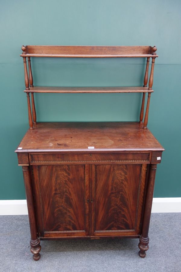 An early 19th century mahogany side/writing cabinet, the open two tier shelf back over a fitted writing drawer and pair of cupboards flanked by turned