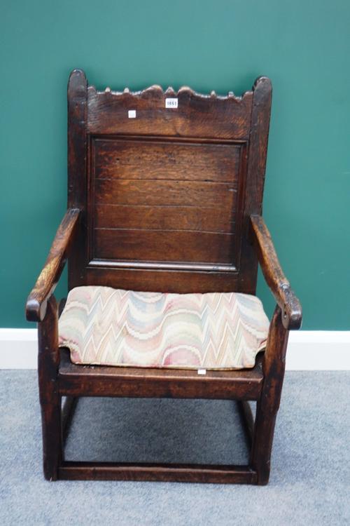 A 17th century oak panel back open armchair with solid seat, on block supports united by perimeter stretcher.