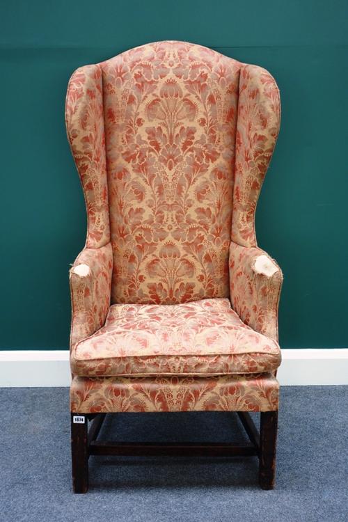 An early 18th century elm framed high wing back armchair, on square supports.