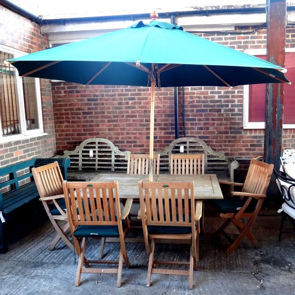 Westminster Teak; a rectangular garden table, 100cm x 150cm, together with six folding chairs with loose cushions and a green parasol, (8)