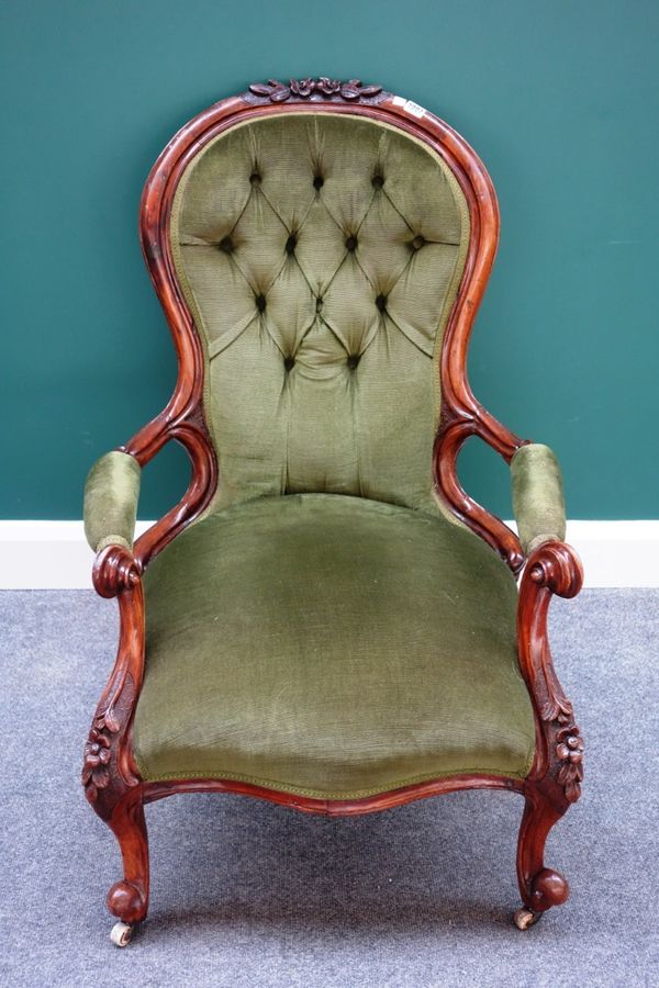 A Victorian carved walnut framed open armchair with serpentine seat on scroll supports.