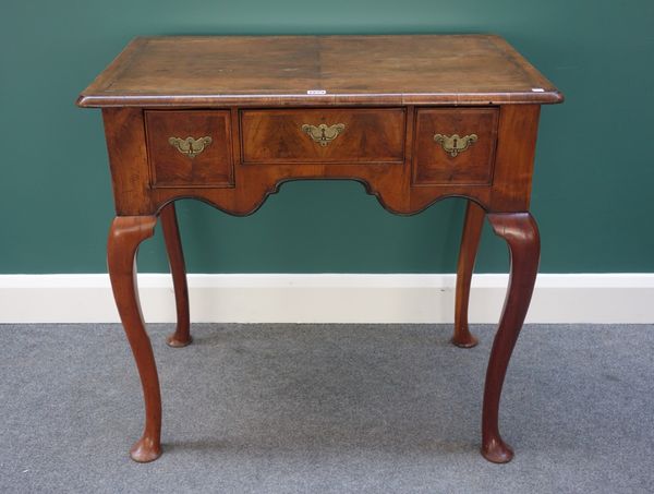 An 18th century figured walnut low boy, the shaped frieze with three drawers, on cabriole supports, 86cm wide.