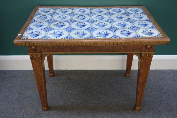 A North European occasional table, the rectangular top inset with twenty four Delft blue and white tiles, the parcel gilt pine base with four tapering