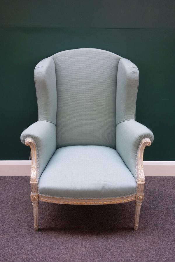 A Louis XVI style parcel gilt grey painted wing back armchair, on bow seat, with tapering fluted supports.