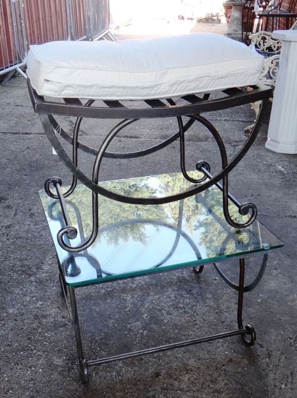 A pair of 20th century black painted iron stools, on X frame bases, with loose cushions, 64cm wide, together with a matching pair of glass top tables,