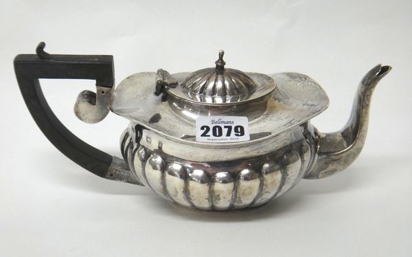 A silver teapot, of oval form, with partly lobed fluted decoration and with a composition handle (the finial lacking), Birmingham 1905, gross weight 3