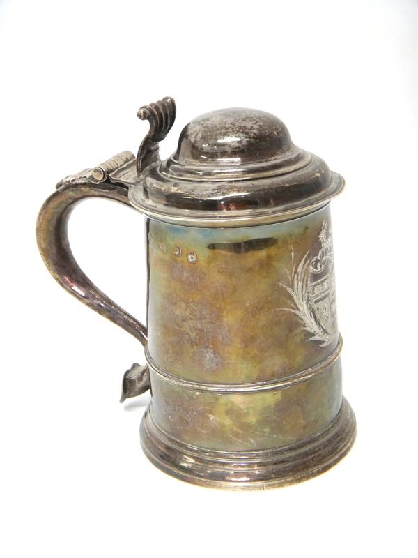 A silver hinge lidded tankard, of tapering cylindrical form, with a domed cover, cast thumbpiece and with a scrolling handle, terminating as a heart,