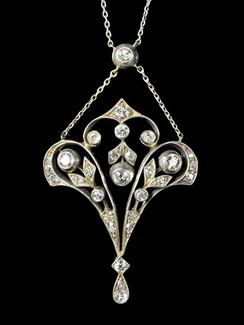 A diamond set pendant, in an Art Nouveau pierced openwork and foliate design, mounted with cushion shaped diamonds and with the three principal diamon