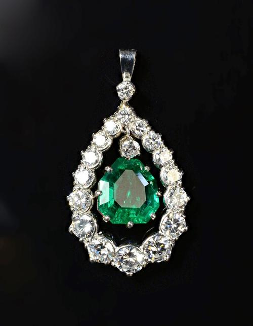 An emerald and diamond pendant, claw set with the shaped step cut emerald at the centre and with a circular cut diamond mounted above, within a drop s