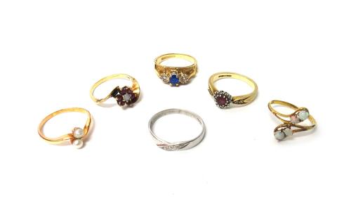 A 9ct gold, opal and ruby set seven stone cluster ring, in a cross over design, a 9ct gold and opal set four stone ring in a twistover design, a 9ct g