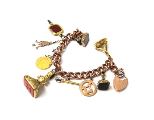 A gold hollow curb link bracelet, on a 9ct gold heart shaped padlock clasp, Birmingham 1907, fitted with nine pendants and charms, to include four sea