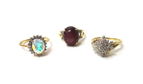 A 9ct gold ring, claw set with an oval cabochon ruby, between diamond set two stone shoulders, a 9ct gold and diamond set cluster ring, mounted with m