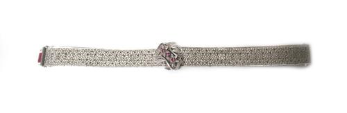 A white gold and red gem set bracelet, in a wide design, having a textured finish, the front with a red gem set floral and foliate motif, on a snap cl
