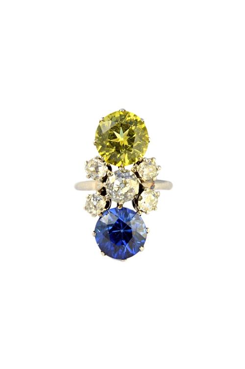 A diamond, synthetic yellow sapphire and synthetic blue sapphire set ring, claw set with the principal cushion shaped diamond at the centre, in a surr