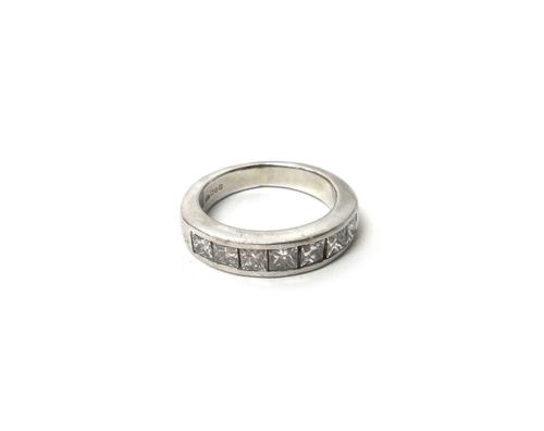 A platinum and diamond set half hoop ring, mounted with a row of seven princess cut diamonds, ring size K, gross weight 9 gms, with a case.