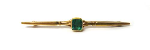 A gold and emerald set single stone bar brooch, mounted with a foil backed cushion shaped emerald, detailed 15 CT.