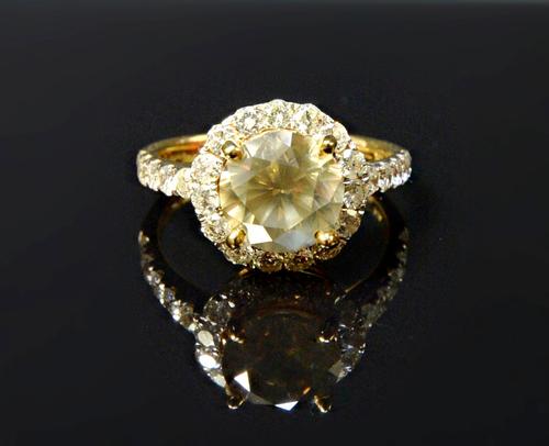 A gold ring, claw set with the principal circular cut fancy yellowish brown diamond at the centre, in a surround of small circular cut diamonds, betwe