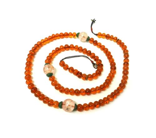 A carved jade Oriental pendant, a carved pale nephrite rectangular plaque, a translucent reconstituted amber bead necklace, seven loose butterscotch c