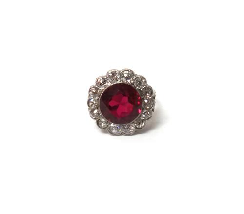 A white gold and platinum, diamond and synthetic ruby set cluster ring, mounted with the circular cut synthetic ruby at the centre, within a surround