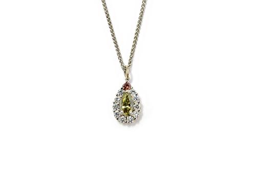 A diamond set drop shaped cluster pendant, claw set with a pale grayish greenish yellow "chameleon" pear shaped diamond to the centre, a champagne/red