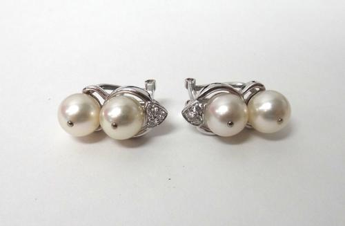 A pair of white gold, cultured pearl and diamond set earclips, each mounted with two cultured pearls and with a diamond set three stone surmount, set