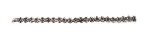 A white gold and sapphire set bracelet, designed as a series of flowerheads, mounted with a row of circular cut sapphires to the centre, detailed 14K,
