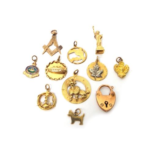 Eleven gold mostly pendants and charms, including; an anchor, a Masonic square and compasses, a heart shaped padlock clasp, an enamelled crest of The