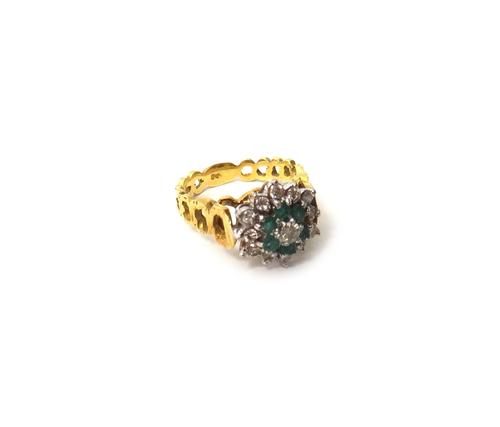 An 18ct gold, emerald and diamond set cluster ring, mounted with the principal circular cut diamond at the centre, in a surround of six circular cut e