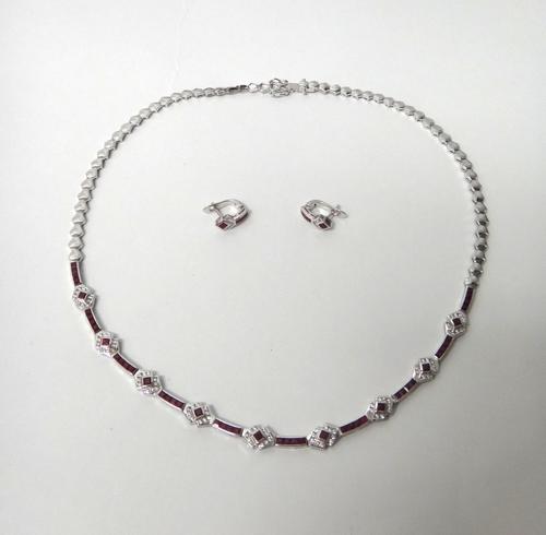 A white gold, diamond and ruby set necklace, the front with a row of nine ruby and diamond set clusters, with ten rows of four calibre cut rubies, mou