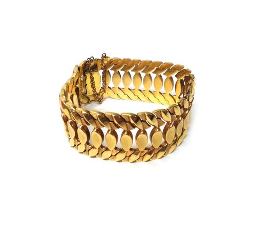 A gold bracelet, in a wide pierced openwork design, with oval motifs to the centre, between stylized foliate sides, on a snap clasp, with a safety cat