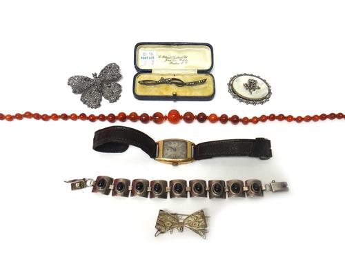 A faceted steel brooch, designed as a butterfly, three further brooches, a single row necklace of graduated cornelian beads, a curved rectangular pane