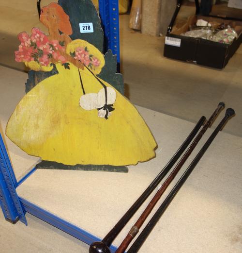 A painted fret cut wooden model of a lady and three various walking sticks, two with silver mounts, (4).