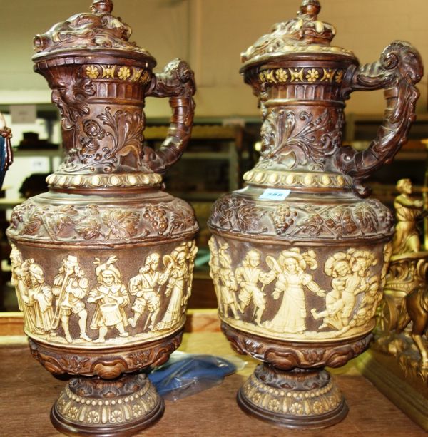 A pair of German pottery lidded ewers moulded with figures, (2).