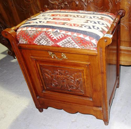An Edwardian walnut lift top piano stool.